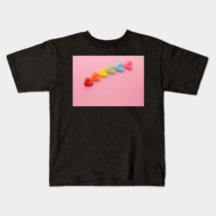 A variety of colorful candy hearts, in a rainbow shape, on a light pink background. Kids T-Shirt